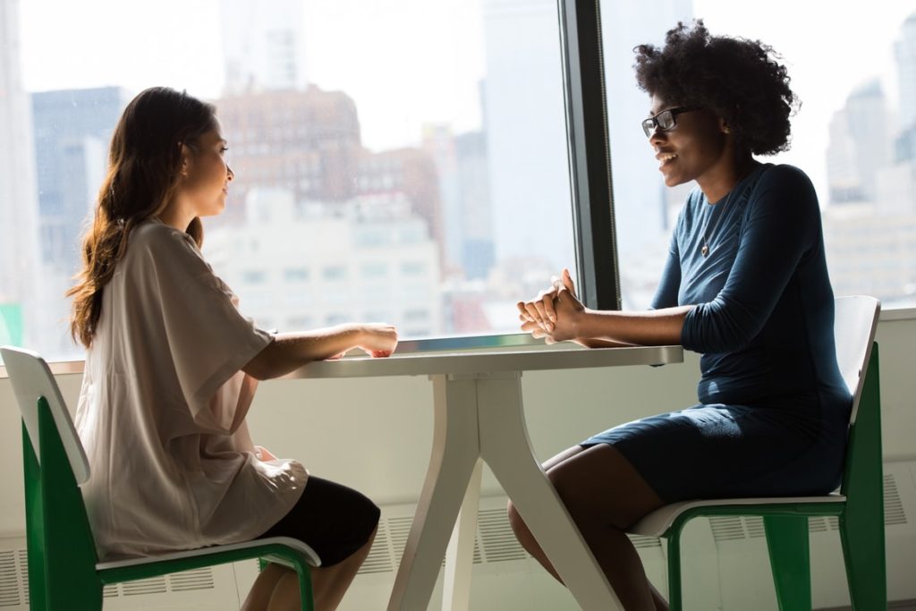 Two woman collaborate at a table, one of the 4 conflict styles at work