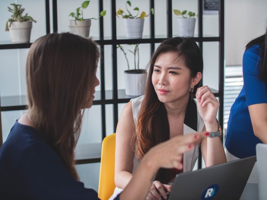 Conflict styles at work: A woman looks unhappy as she listens to her co-worker.