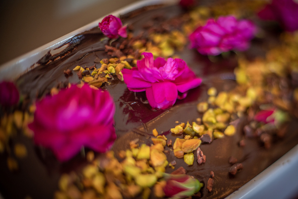 Pink flowers and nuts scattered across a chocolate cake